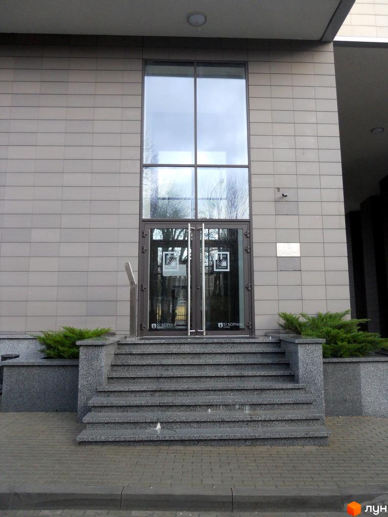 Вхідні двері житлового комплексу ЖК Crystal Park з гранітними сходами та зеленими насадженнями на прибудинковій території.