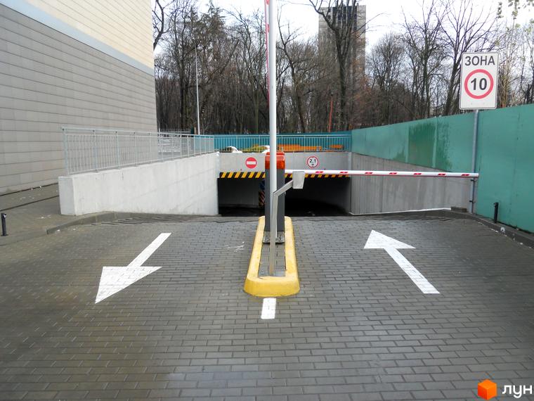 В'їзд до підземного паркінгу житлового комплексу ЖК Crystal Park з асфальтованою територією та знаками обмеження швидкості.