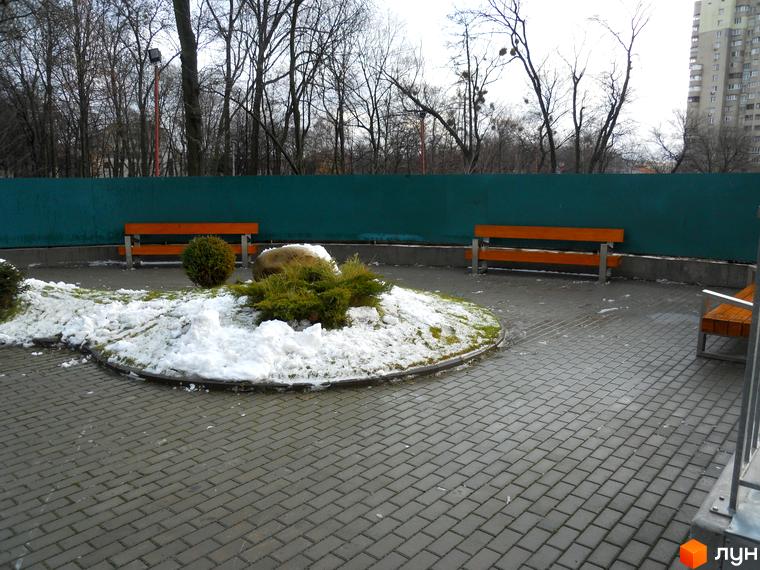 Зовнішній вигляд прибудинкової території житлового комплексу Crystal Park з лавками та зеленими насадженнями.