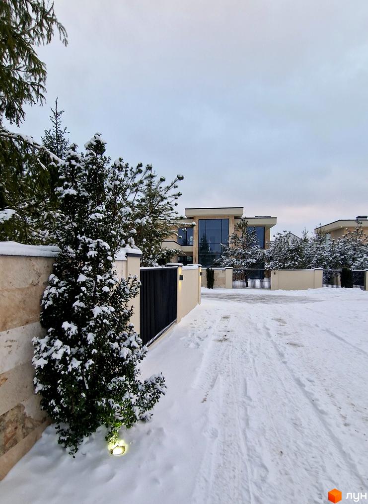 Котеджне містечко Riviera City Park у зимовому ландшафті з сучасними будинками та огородженою територією. Навколо новобудови засніжені дерева та доглянута прибудинкова територія.