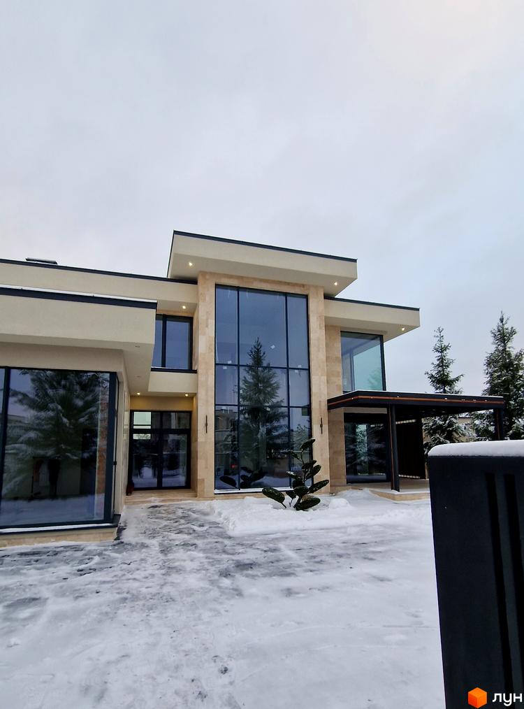 Зображення будинку в Котеджному містечку Riviera City Park. Фасад будинку з великими вікнами та засніжена прибудинкова територія.