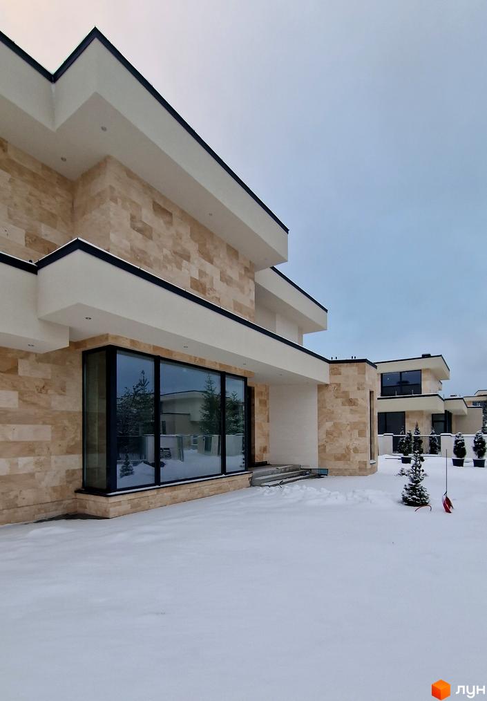 Котеджне містечко Riviera City Park. Будинки з бежевим фасадом та великими вікнами на тлі засніженої території з ялинками.