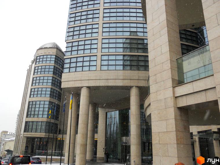 Житловий комплекс H-Tower з сучасною архітектурою та великими вікнами. Прибудинкова територія з зеленими насадженнями та пішохідними доріжками.