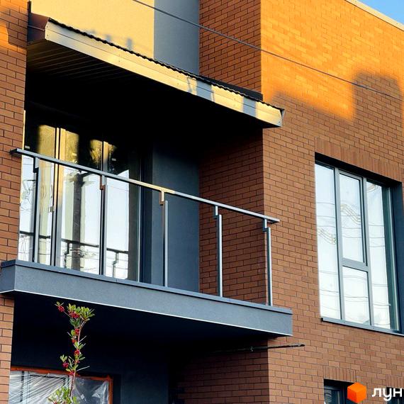 Фасад житлового комплексу КМ Панич 3.0 з цегляним оздобленням та балконом. Навколо будинку видно елементи прибудинкової території.