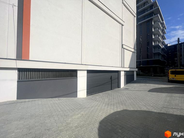 Житловий комплекс City Line має світлий фасад з вертикальною помаранчевою смугою та гаражними воротами. Прибудинкова територія вимощена бруківкою.