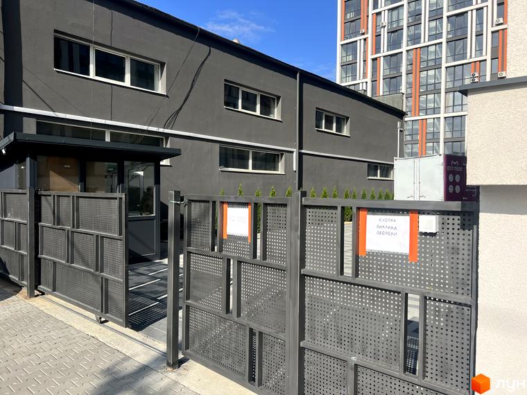 Вигляд будівлі Житлового комплексу City Line з сірим фасадом та білими вікнами. На передньому плані сіра металева огорожа.