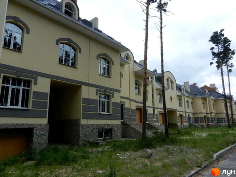 Зображення Котеджного містечка Сосновий бір: жовті будинки з сірим оздобленням, великі вікна та акуратна прибудинкова територія з газоном. Вигляд на фасади котеджів.