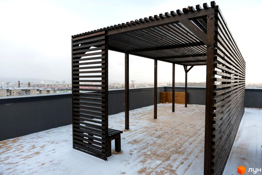 Дерев'яна пергола на даху Житлового комплексу Сонячна Долина, що пропонує зону відпочинку з видом на місто взимку.