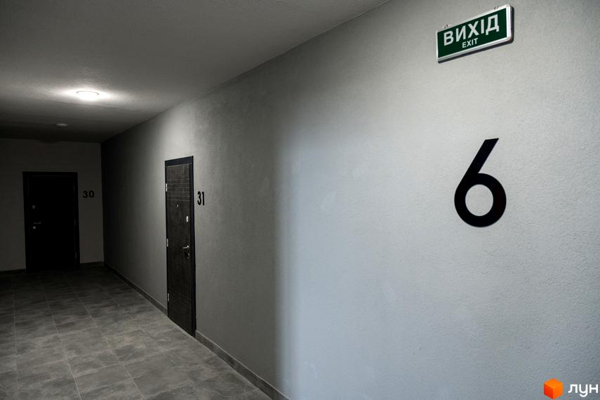 Коридор Житлового комплексу Сонячна Долина з дверима квартир 30 і 31, вказівником виходу та номером поверху 6.
