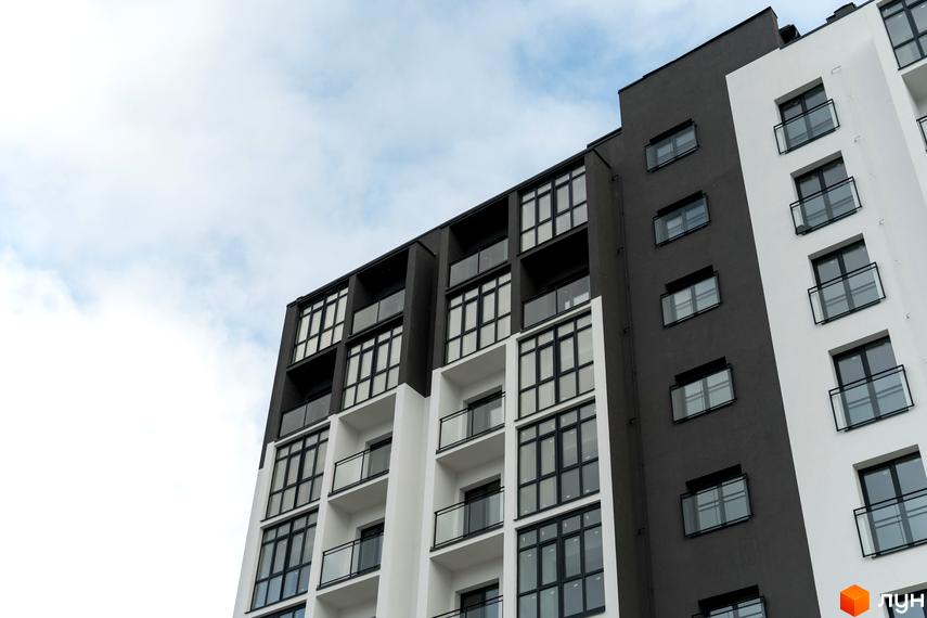 Фасад Житлового комплексу Сонячна Долина з темно-сірими та білими секціями, великими вікнами та скляними балконами.