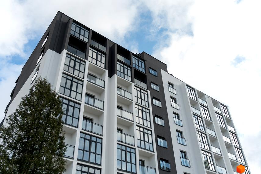 Багатоповерховий житловий будинок Житлового комплексу Сонячна Долина з чорно-білим фасадом та скляними балконами. Перед будинком видно високе зелене дерево.