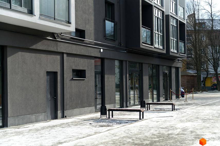Темно-сірий фасад Новобудови Сонячна Долина з великими вікнами та скляними балконами. Прибудинкова територія з лавками, вкрита снігом.