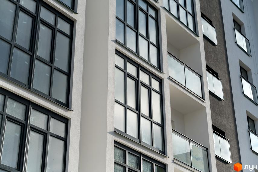 Фасад Житлового комплексу Сонячна Долина з білими та темно-сірими стінами, великими вікнами і балконами зі скляними огорожами.