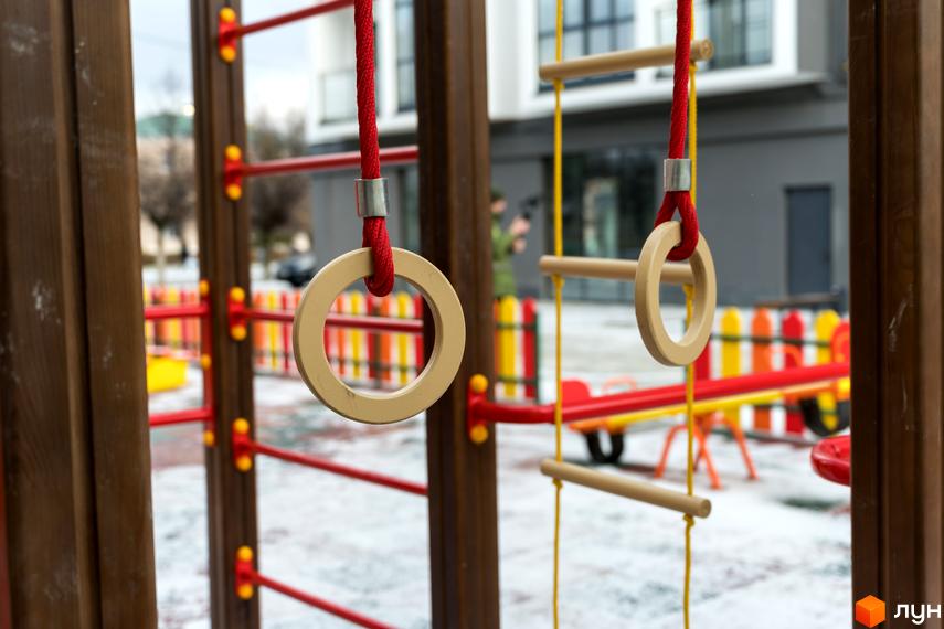 Дитячий майданчик біля новобудови ЖК Сонячна Долина, з гімнастичними кільцями та гіркою. Територія комплексу вкрита снігом.