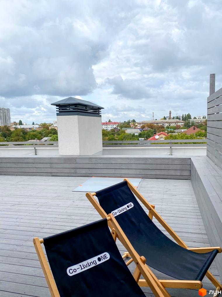 Тераса житлового комплексу Coliving ONE Nivki з шезлонгами та видом на місто. Відпочинок на свіжому повітрі на даху новобудови.