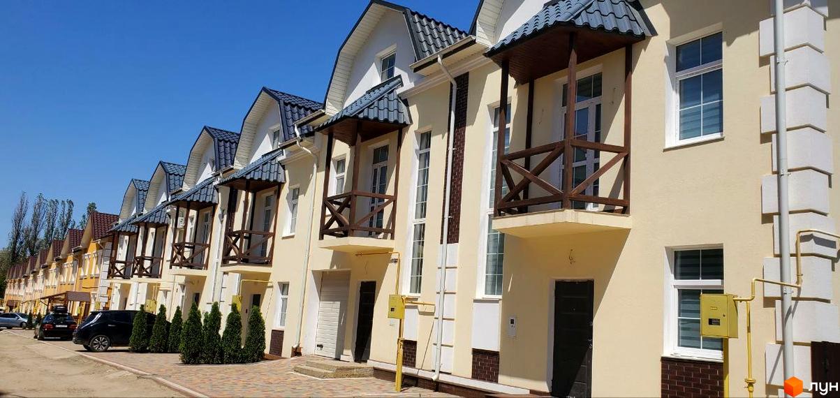 Фасади таунхаусів Таунхаус „Гарден Хаус'' світлого кольору з дахами темно-сірого відтінку та дерев'яними балконами. Прибудинкова територія викладена бруківкою з декоративними кущами.