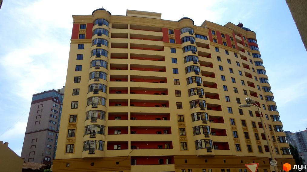 Житловий комплекс Златоустівський з жовтою фасадною обробкою та балконами. Прибудинкова територія з освітленням та зеленими насадженнями.