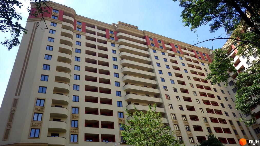 Житловий комплекс Златоустівський з балконами та великими вікнами. Прибудинкова територія озеленена деревами.