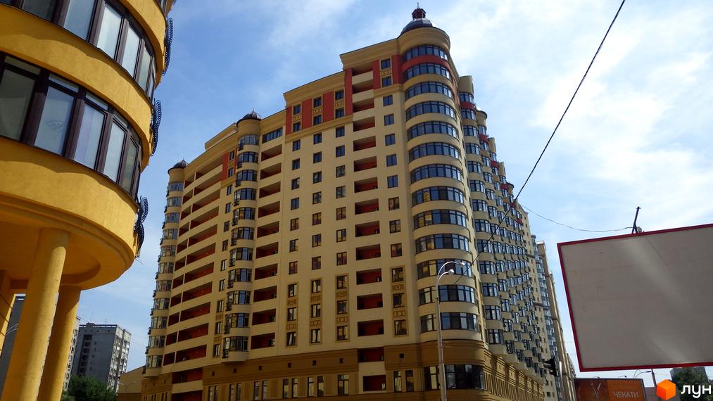 Житловий комплекс Златоустівський - багатоповерховий будинок з вигнутими фасадами та балконами. Зовнішній вигляд новобудови з вікнами та червоними елементами.