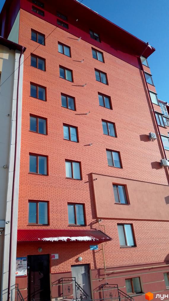 Зовнішній вигляд цегляної новобудови на вулиці Березова, 4а, з червоним дахом та кондиціонерами на фасаді. Будівельний проєкт з великою кількістю вікон.