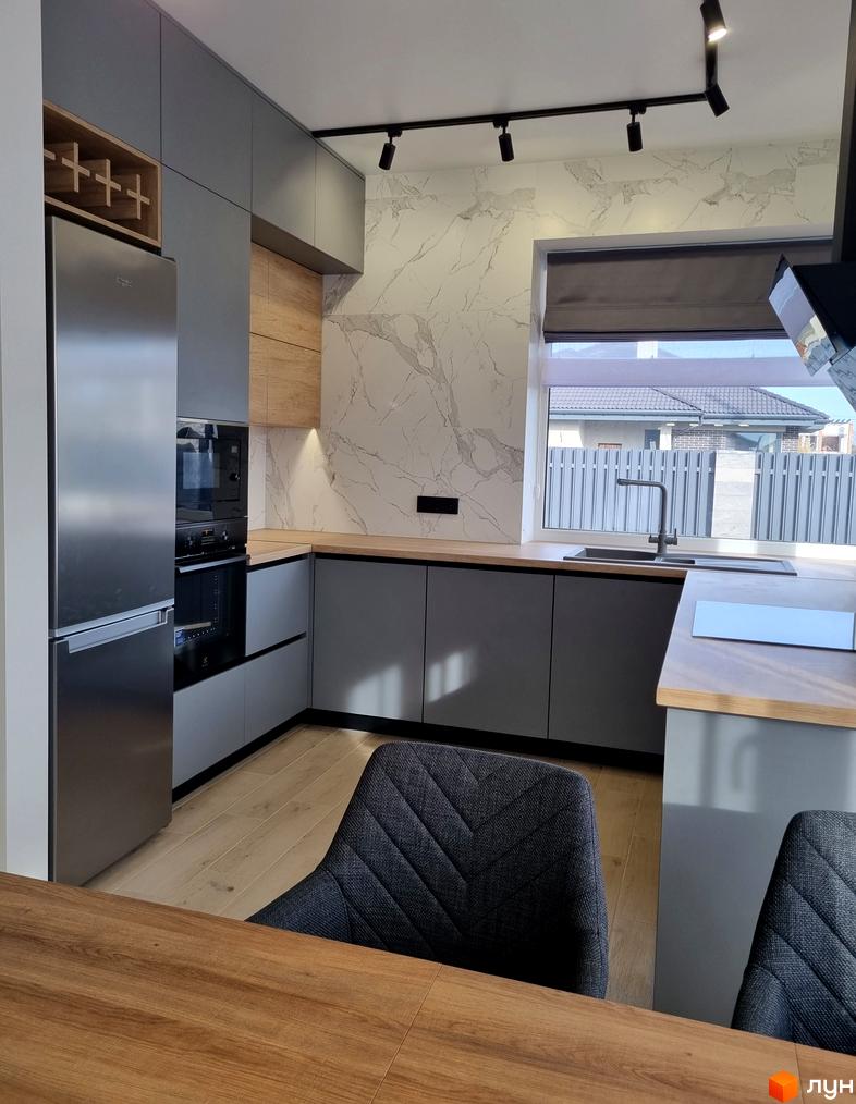 Сучасна кухня з сірими фасадами та дерев'яними акцентами. Велике вікно з видом на приватний сектор.