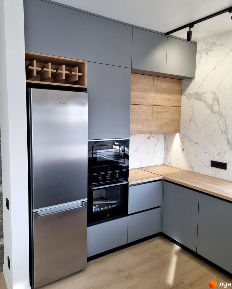 Сучасна кухня з сірими фасадами та дерев'яними акцентами. Вбудована техніка та полиця для пляшок. КМ Сонячний - комфортне житло.