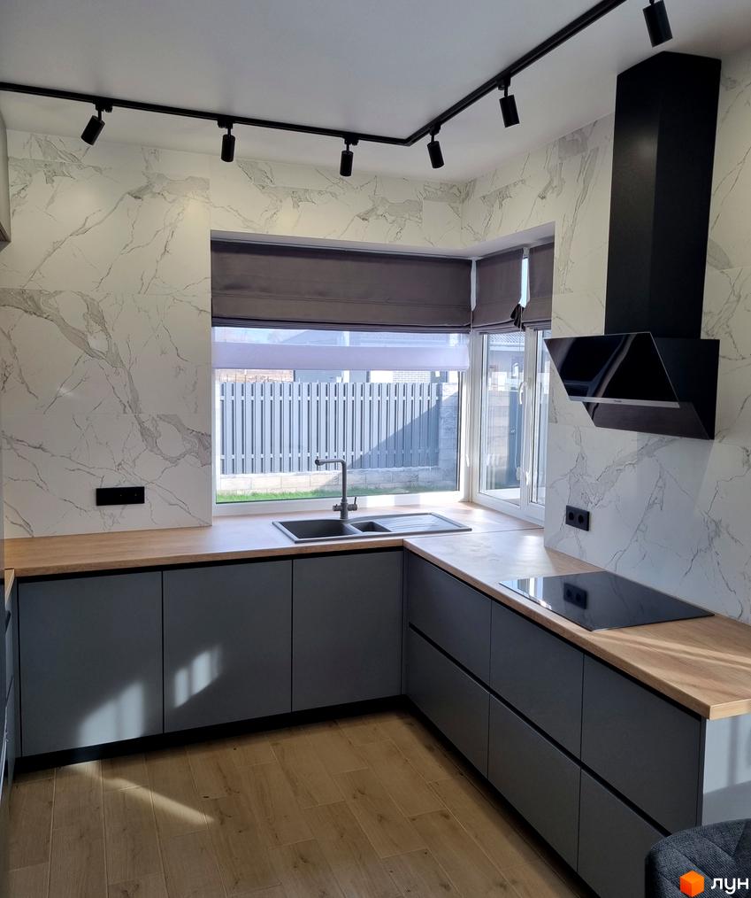 Сучасна кухня з мармуровим фартухом та сірими фасадами. Вбудована техніка та велике вікно з видом на паркан.