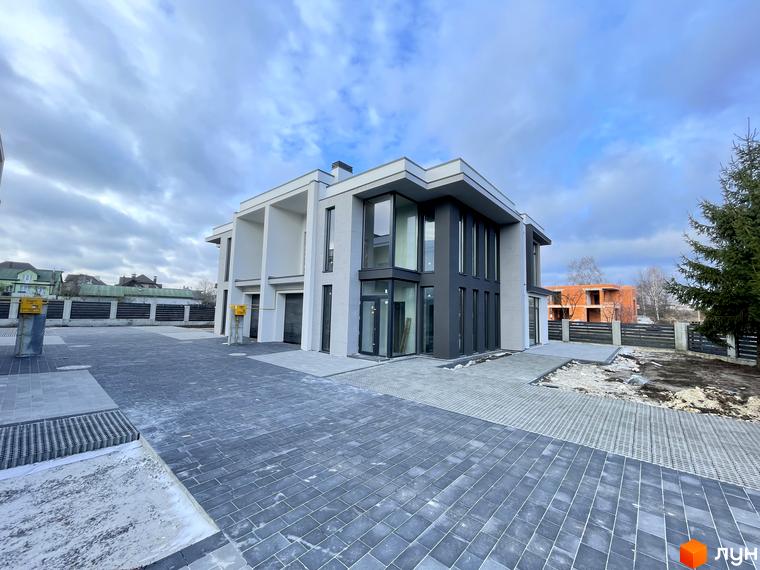 HEG WOW HOUSE дуплекси - сучасний житловий комплекс з двома поверхами, сірими та білими фасадами, великими вікнами та вимощеною сірою бруківкою прибудинковою територією.