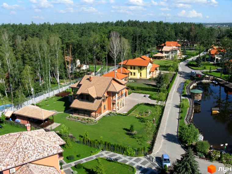 Зовнішній вигляд будинків у Котеджному містечку Bosco Village з зеленими територіями та доріжками. Прибудинкова територія з водоймою та парком.