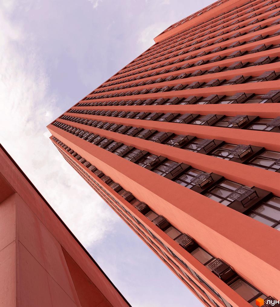 Житловий комплекс DOCK32: висока будівля теракотового кольору з багатьма вікнами та зовнішніми блоками.
