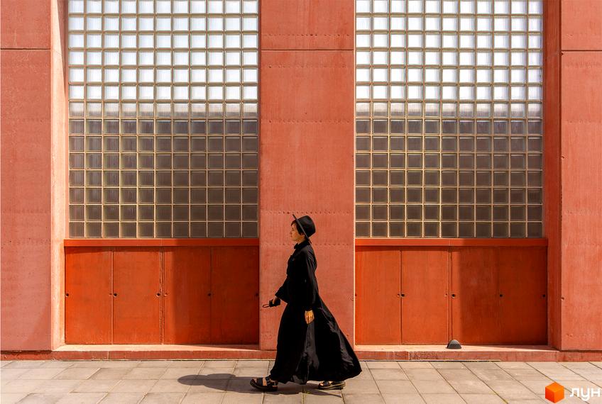 Будівля Житлового комплексу DOCK32 має червоно-коричневий фасад з великими секціями склоблоків та глухими панелями. Перед входом розташований вимощений тротуар.