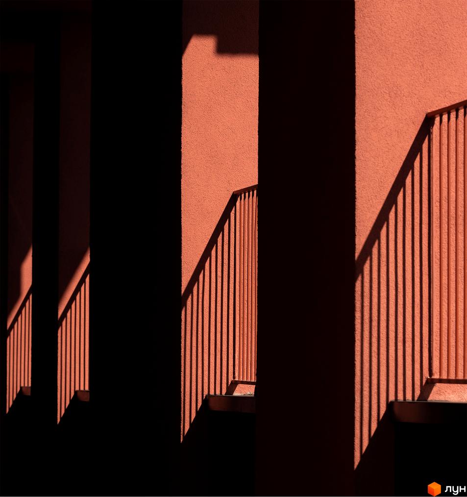 Фасад будинку DOCK32: червоно-коричнева текстурована стіна з чіткими тінями від перил.