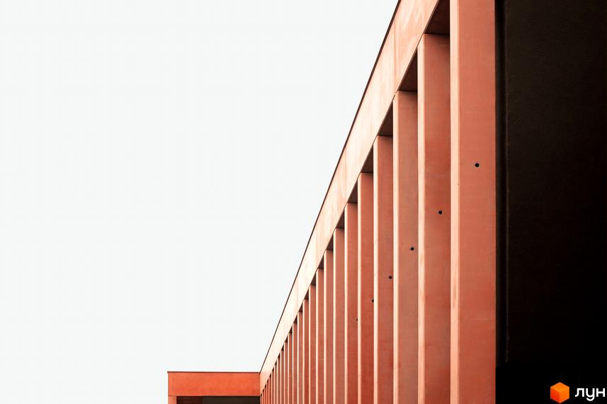 Фасад Житлового комплексу DOCK32 з вертикальними елементами теракотового кольору на тлі світлого неба. Архітектура будівлі має чіткі лінії.