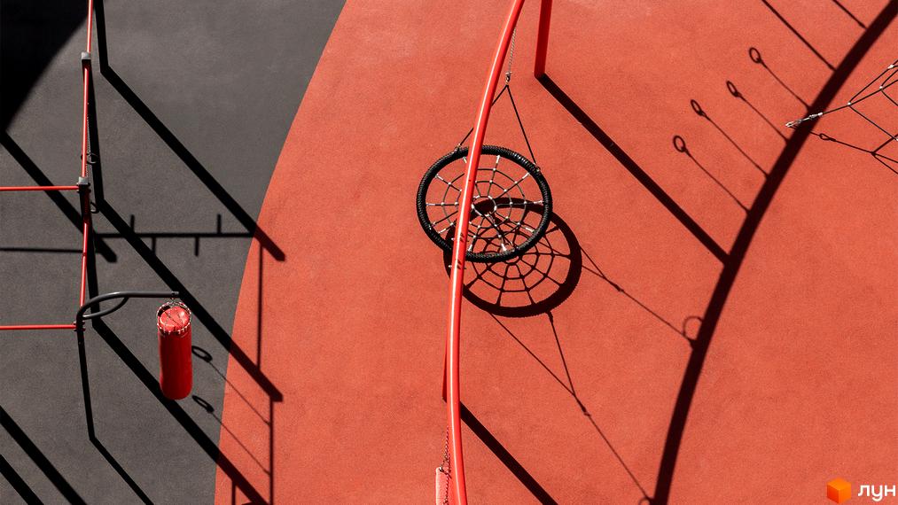 Прибудинкова територія DOCK32: спортивний майданчик з червоними тренажерами, боксерською грушею та круглою гойдалкою.