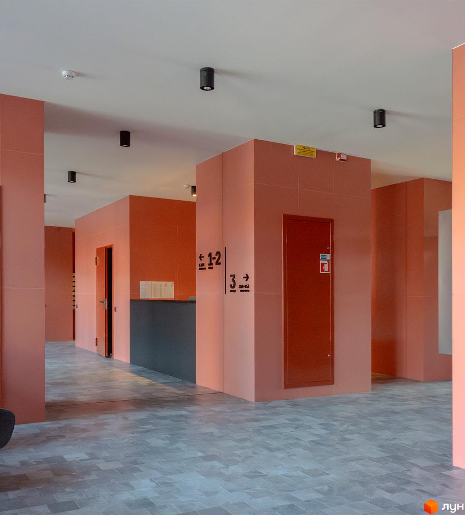 Інтер'єр холу DOCK32 з теракотовими стінами, сірою плиткою на підлозі та вказівниками напрямків.