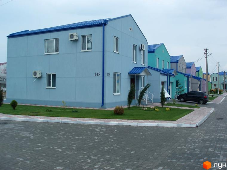 Котеджне містечко Блакитне озеро. Двоповерхові будинки блакитного кольору з синіми дахами. Перед будинками газон з невеликими деревами та доріжки з бруківки.