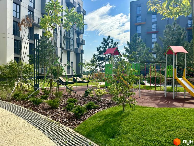 Житловий комплекс Проект Панорама. Сучасний дитячий майданчик з гіркою та гойдалками біля багатоповерхових будинків.