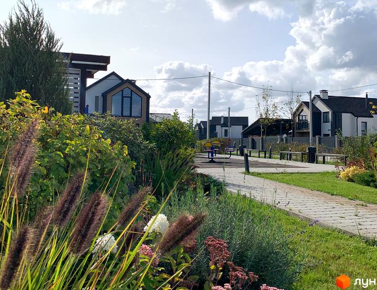 Котеджне містечко КМ Європа: сучасні будинки з великими вікнами та доглянута прибудинкова територія з дитячим майданчиком та зонами відпочинку.