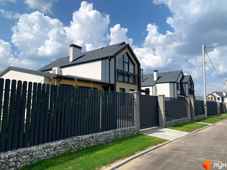 Котеджне містечко КМ Європа: фасади будинків з темним дахом та великими вікнами, огороджена територія з парканом та озелененням.