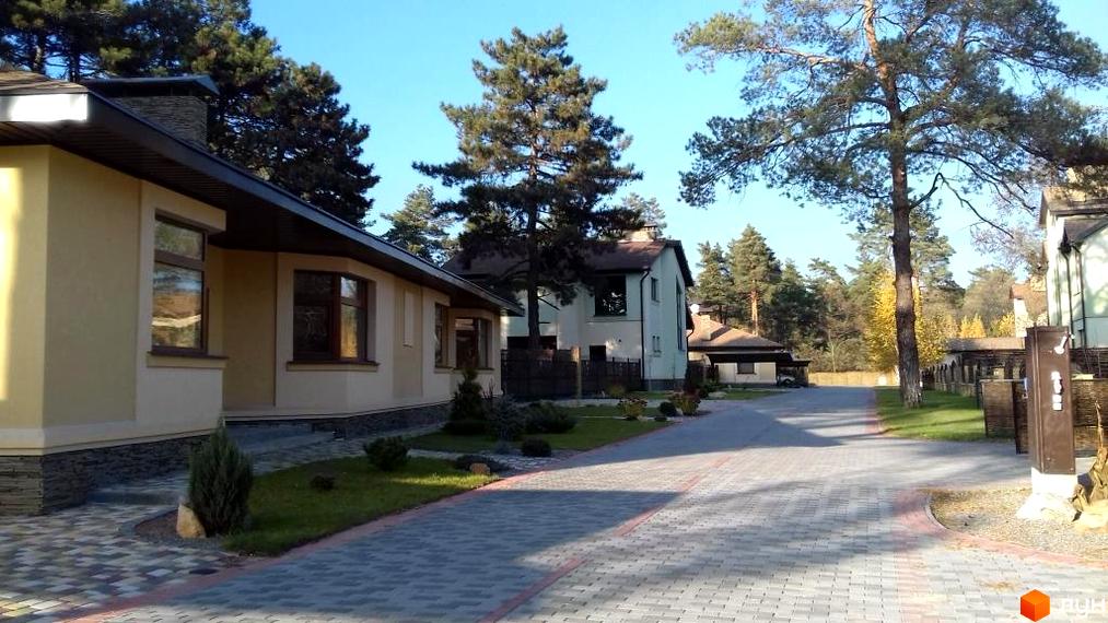 Зовнішній вигляд будинків у житловому комплексі КМ Шишкино з прибудинковою територією та зеленими насадженнями.