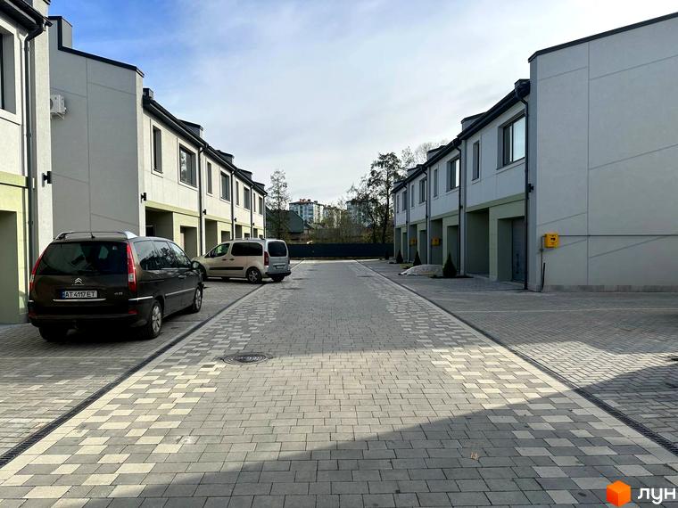 Зовнішній вигляд таунхаусів Садовий Клуб з сірими фасадами та прибудинковою територією з бруківки. Фото новобудови.