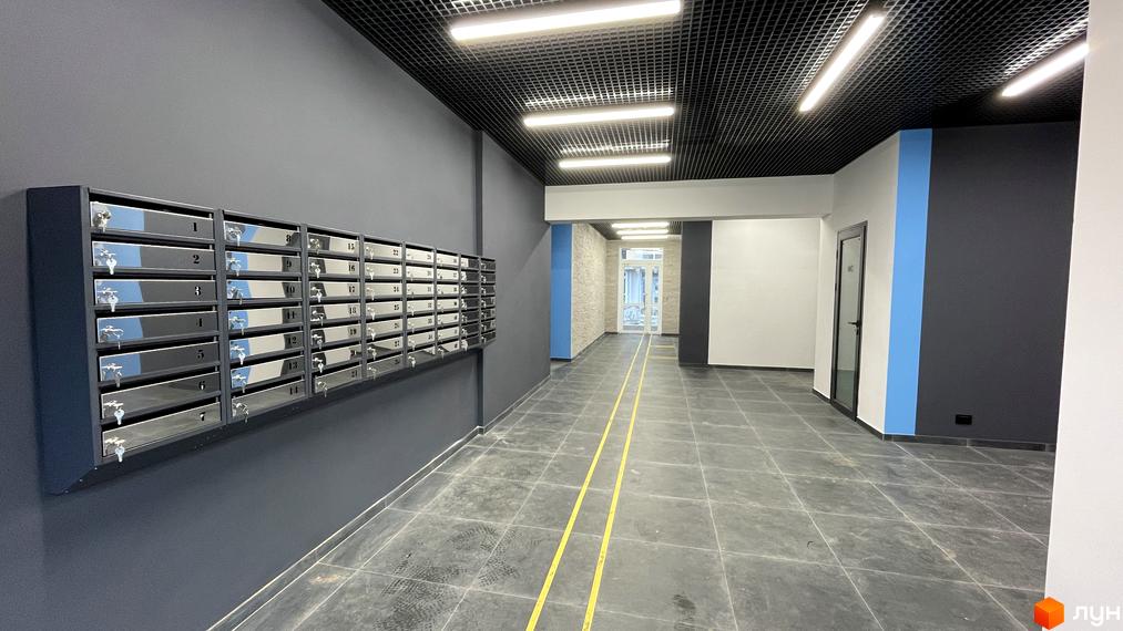 Інтер'єр під'їзду у Житловому комплексі One Family з поштовими скриньками та плиткою на підлозі. Вигляд коридору з освітленням на стелі.