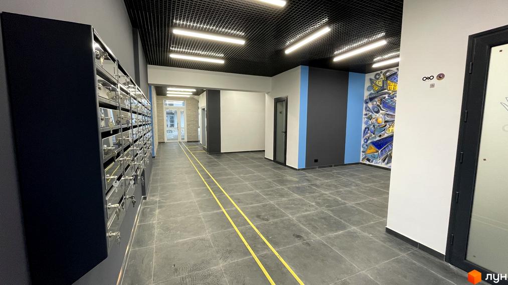 Вестибюль житлового комплексу One Family з поштовими скриньками, чорною стелею, сірою плиткою на підлозі та яскравим муралом.