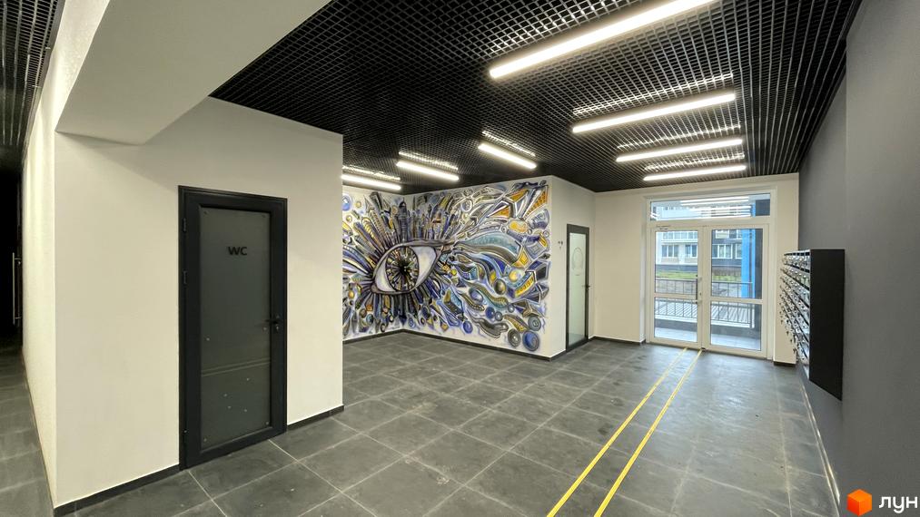 Інтер'єр холу в Житловому комплексі One Family з дверима, стінами та підлогою в сірих тонах, а також яскравим малюнком на стіні.