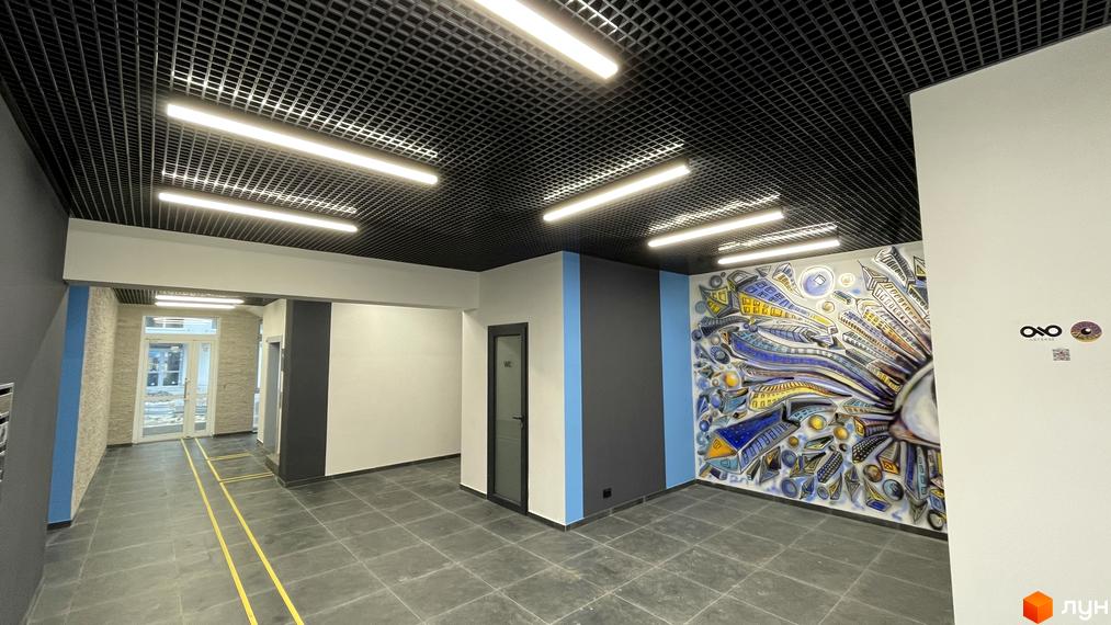 Інтер'єр приміщення у Житловому комплексі One Family з чорною стелею та світильниками. На стіні художнє оформлення.