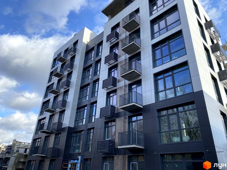 Зовнішній вигляд житлового комплексу Forest Hill з панорамними вікнами та балконами. Будинок має сучасний дизайн з сірими та темними фасадами.