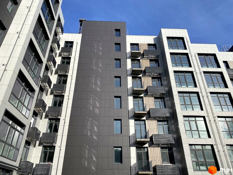 Висотна будівля ЖК Forest Hill з панорамними вікнами та балконами, фасад виконаний у світлих та темних тонах. Яскраве блакитне небо.