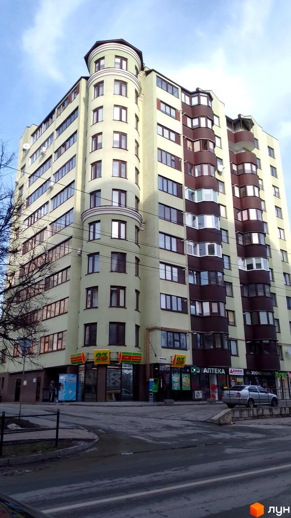 Житловий комплекс: багатоповерховий будинок світло-зеленого кольору з округлою частиною та коричневими балконами. На першому поверсі магазини.