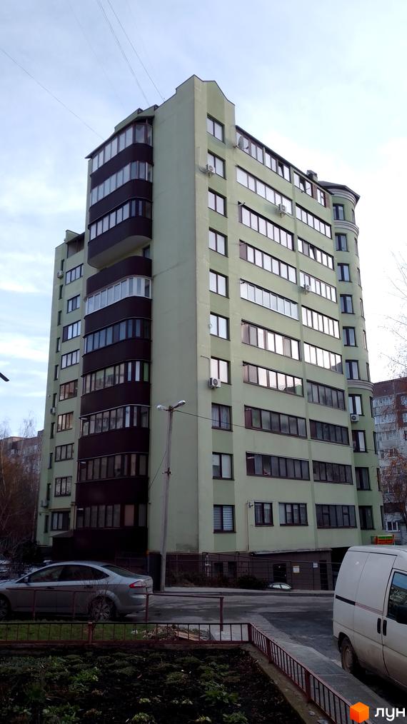 Новобудова на вул. Симоненка, 5а: багатоповерховий будинок світло-зеленого кольору з темно-коричневими балконами та прибудинковою територією.