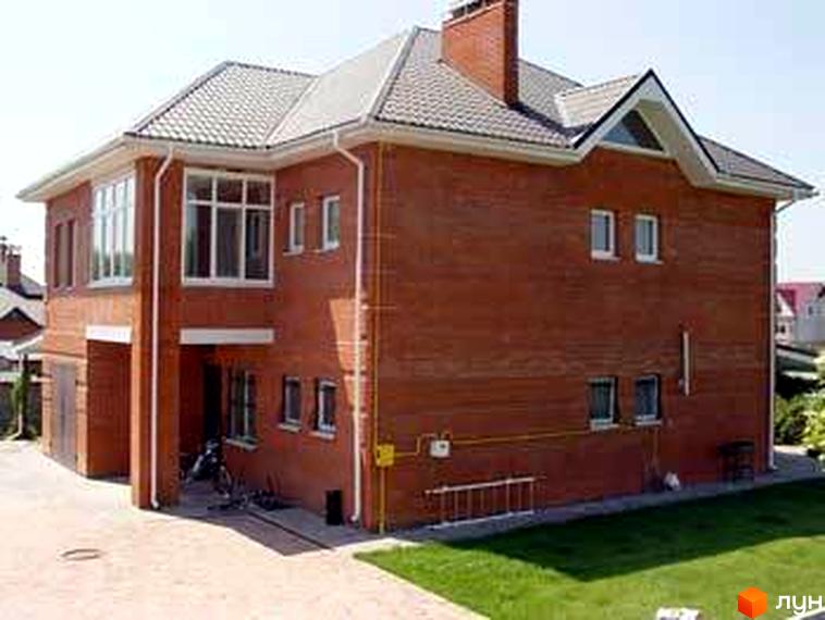 Будинок житлового комплексу КМ Нові Петровці з червоної цегли, прибудинкова територія з газоном.